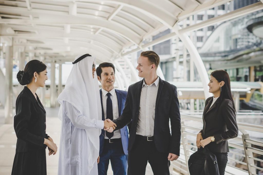 business partners in dubai greeting one another by handshaking on the way to office.